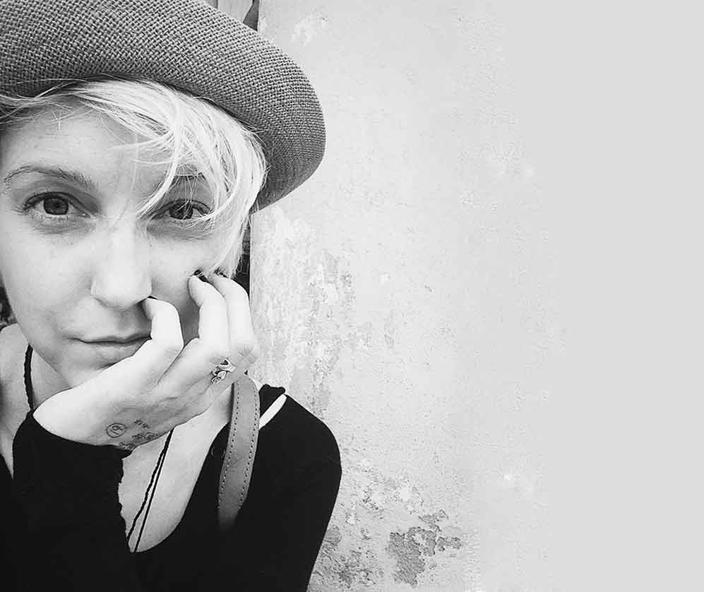 profile picture of a woman wearing a hat, resting her chin on her hand